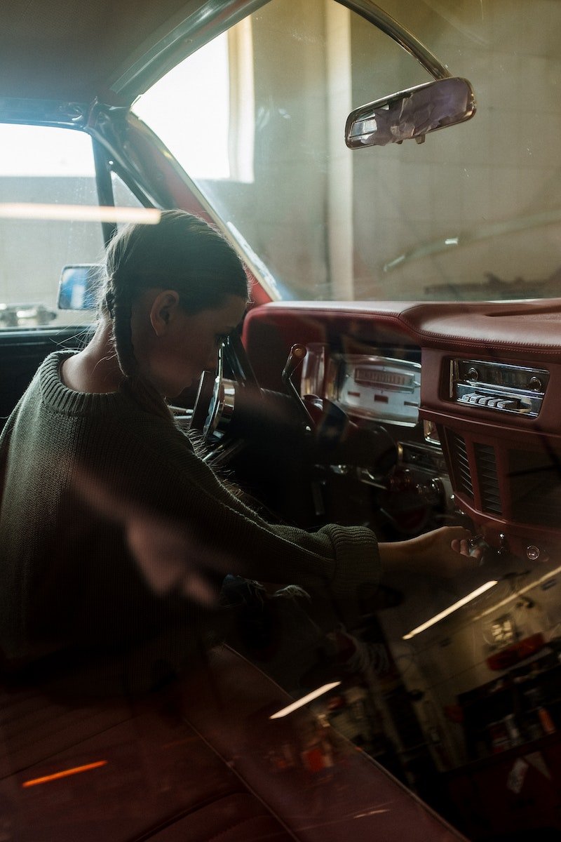Woman in Gray Sweater Sitting on Black and Red Car