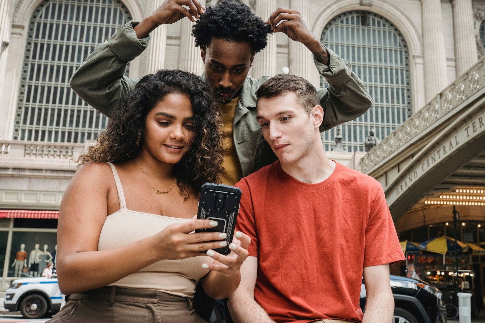 Focused multiethnic friends browsing smartphone on street